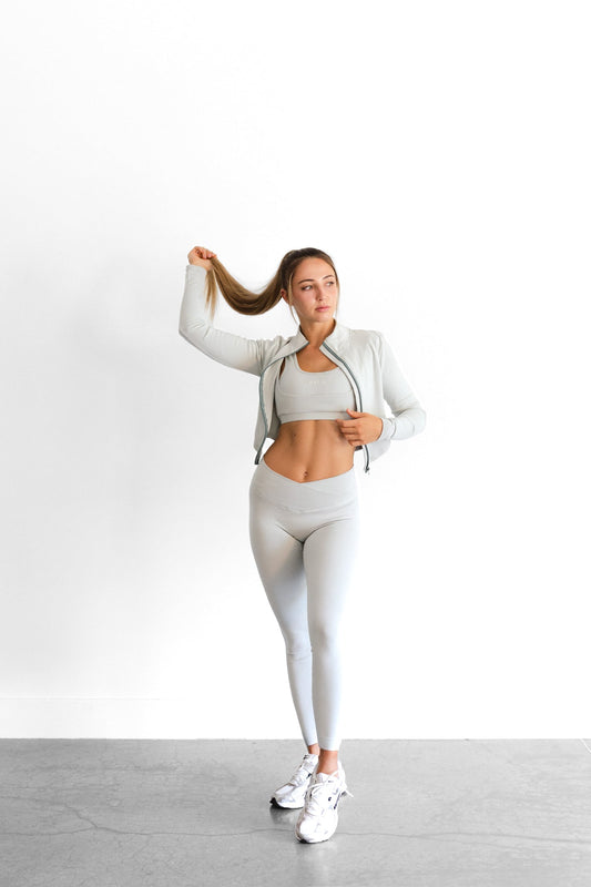 Full-length view of the sage SYLA Sculpt Jacket worn open over matching bra and leggings