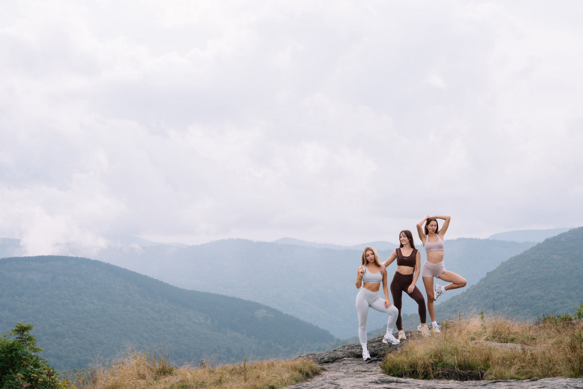 Three women in SYLA organic cotton activewear standing on a rocky mountain overlook above the Blue Ridge