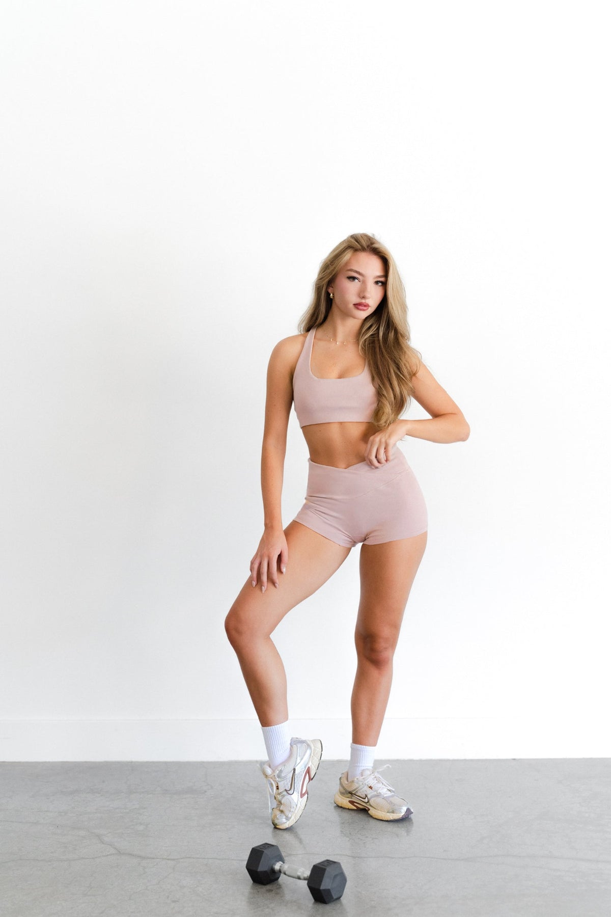Full-length view of the blush SYLA Racer Set, racerback top and high-waist short with sneakers